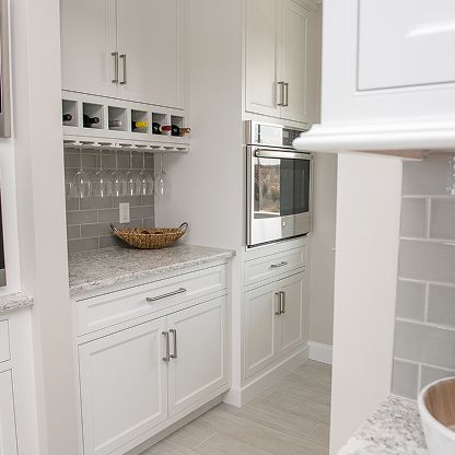 Bright white kitchen with built-in cabinets, wine glasses, and a microwave oven