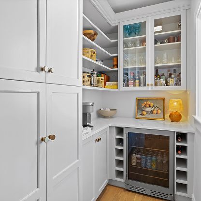 White kitchen pantry with open shelves, glass cabinets, jars, snacks, and a wine fridge.