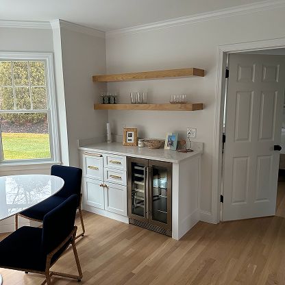 Dining room with white cabinet, wooden shelves, and glass-door beverage cooler by a window and door