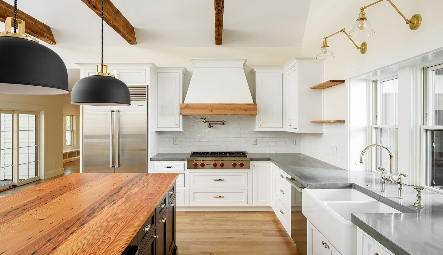 Bright modern kitchen with white cabinets, wood beams, marble counters, and a large wooden island