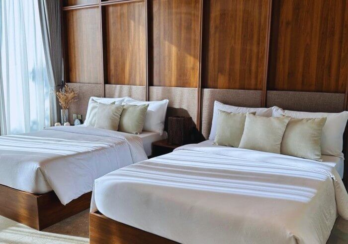 A hotel room with two beds and a wooden wall.