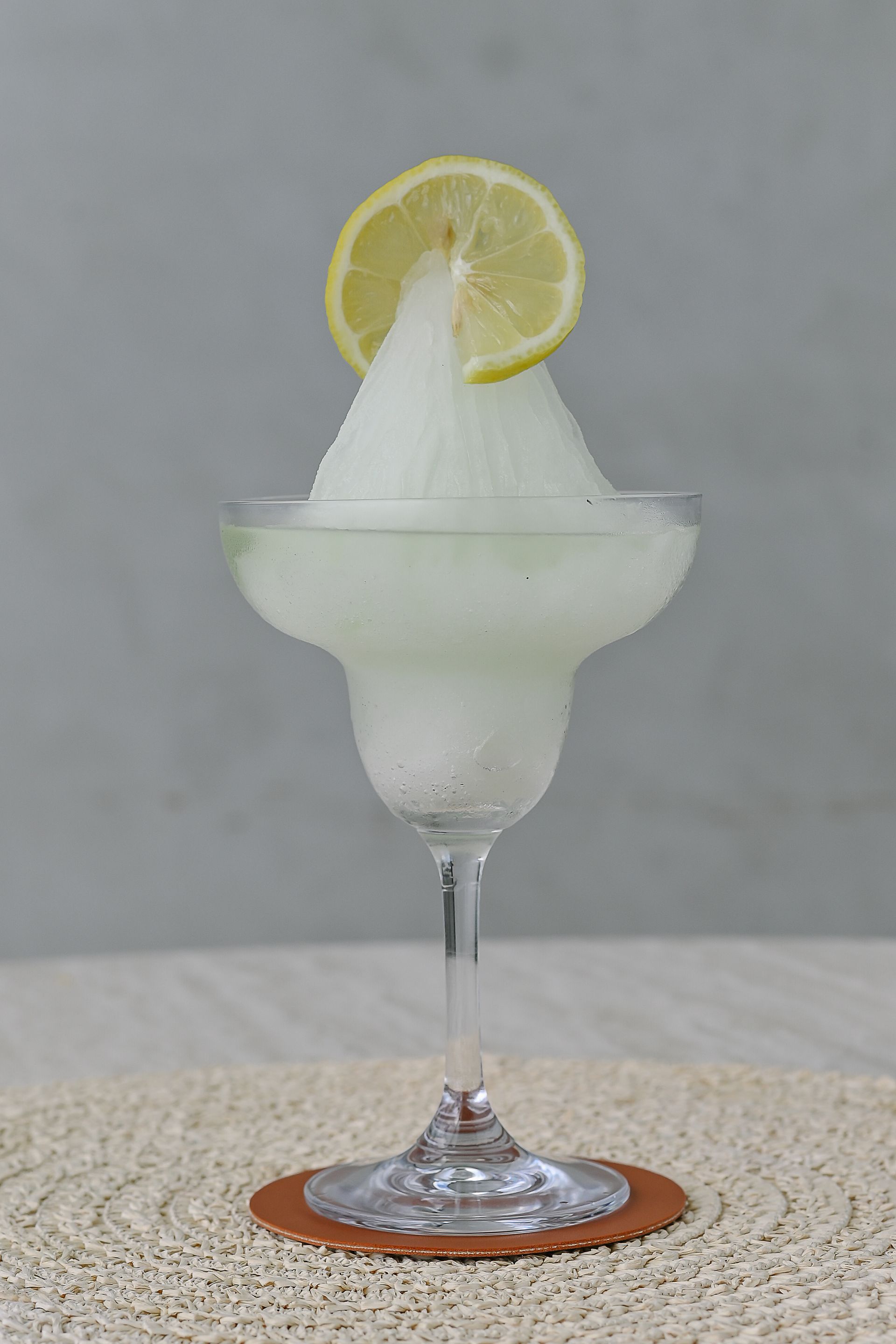A margarita in a martini glass with a slice of lime on top.