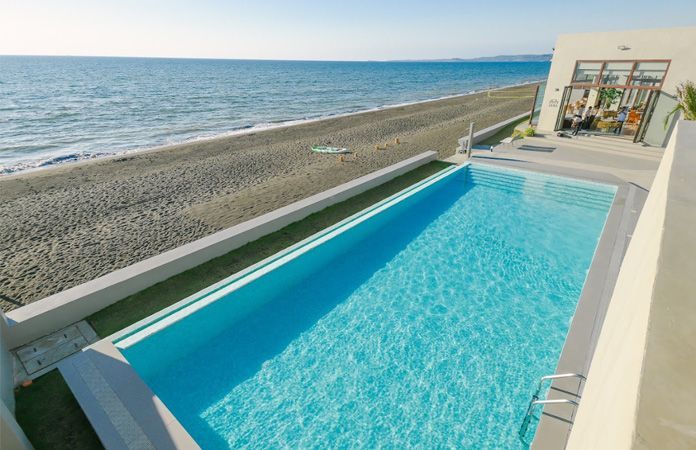 There is a large swimming pool next to the ocean.