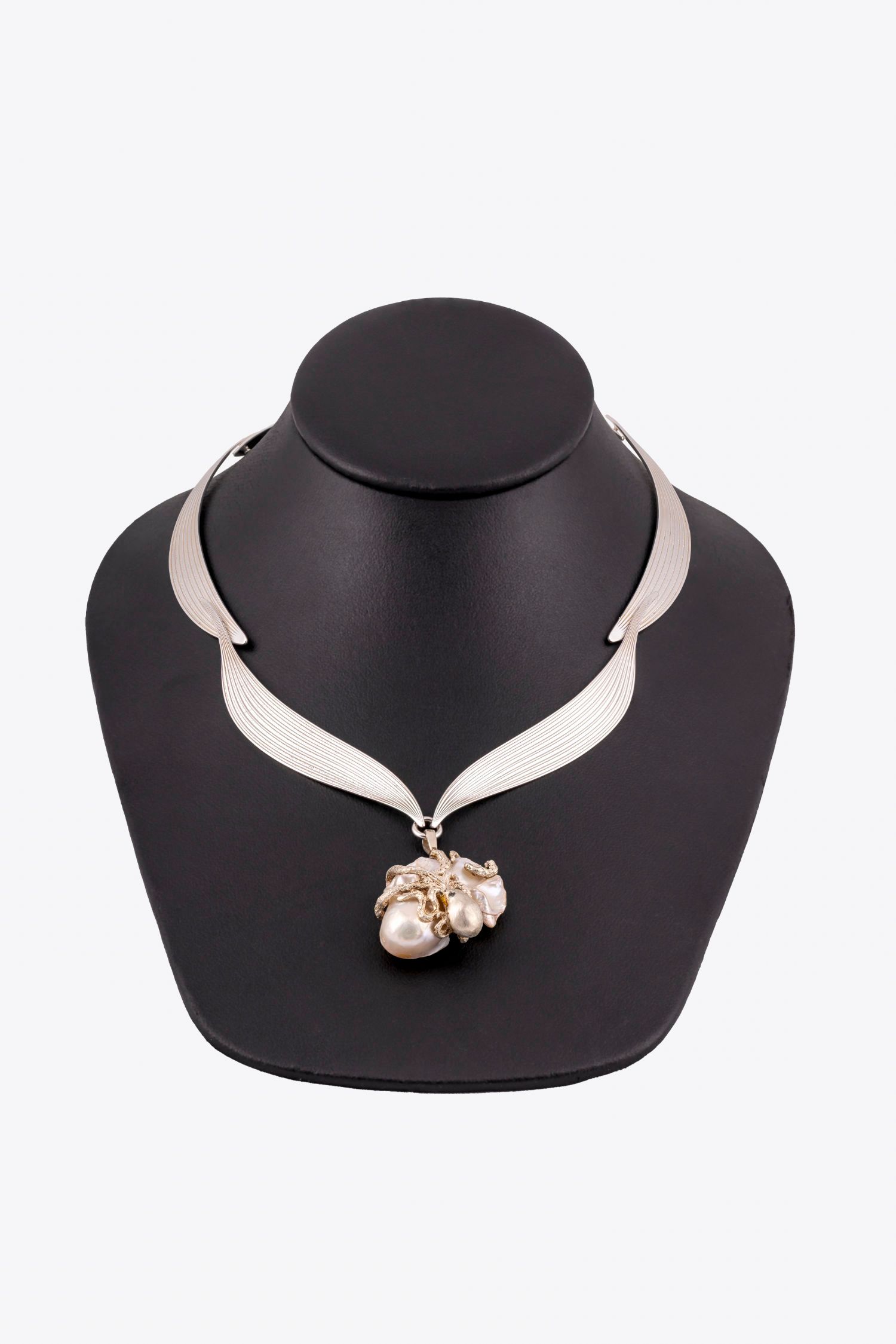 A necklace is on a black mannequin with a white background