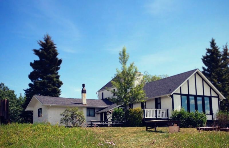 A large white house sits in the middle of a grassy field