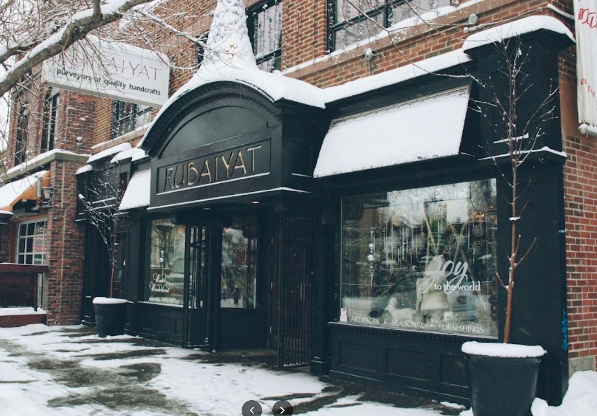 A brick building with a black awning is covered in snow.