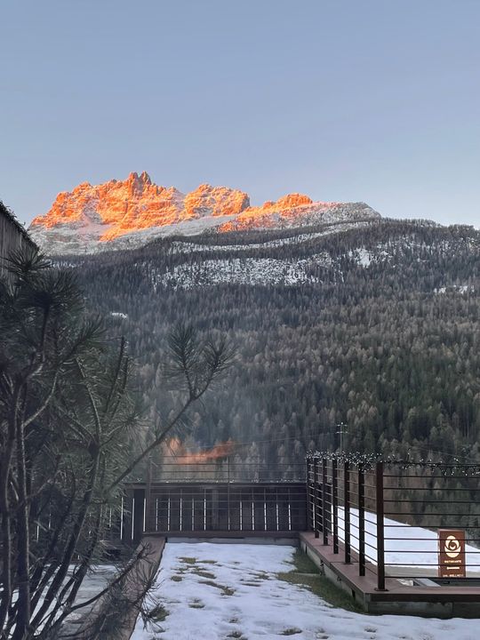 Accogliente camera d'albergo con letto e finestra aperta che incornicia una vista sulle montagne.