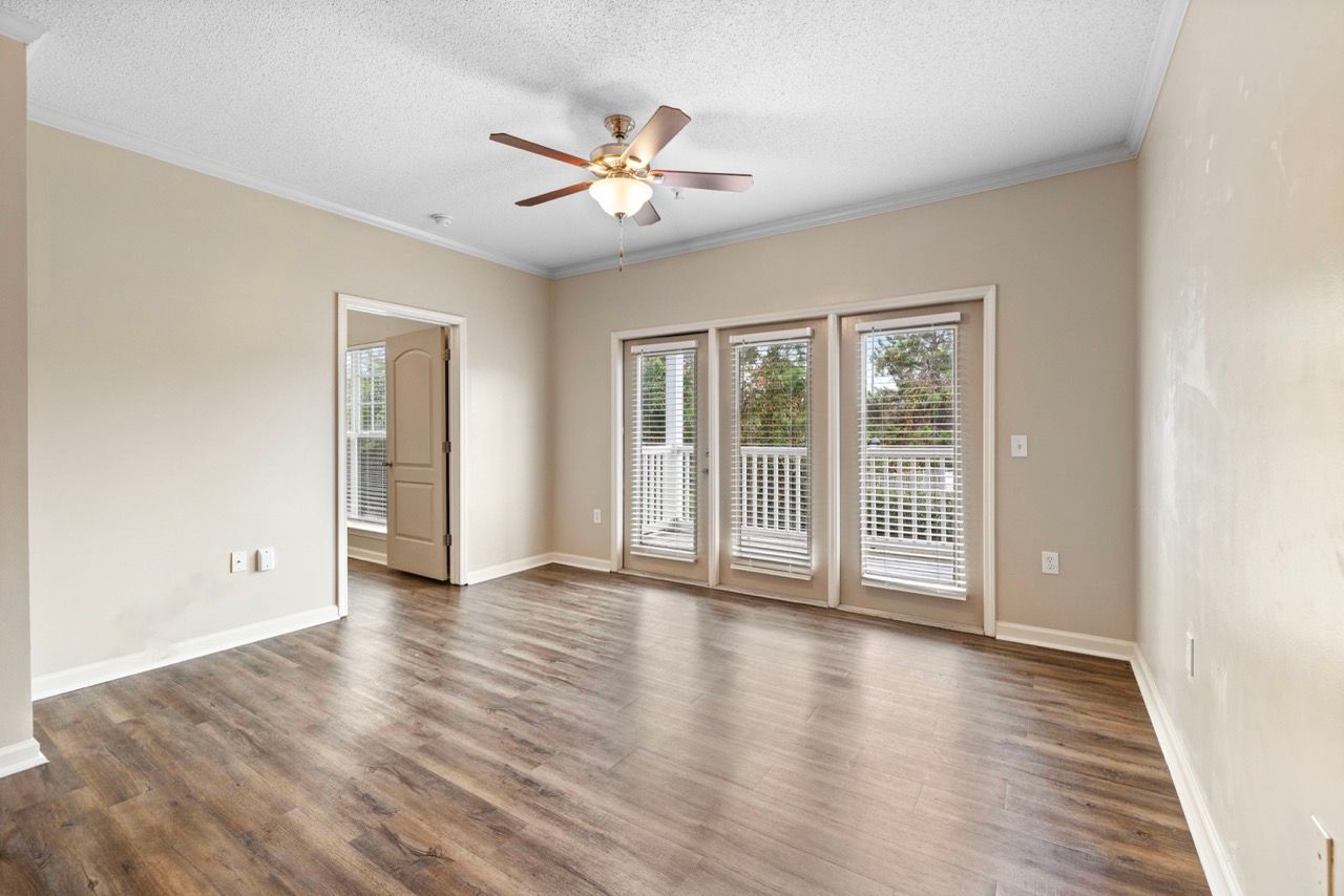 Living room with wood-look flooring, beige walls, a ceiling fan, and glass doors with blinds.
