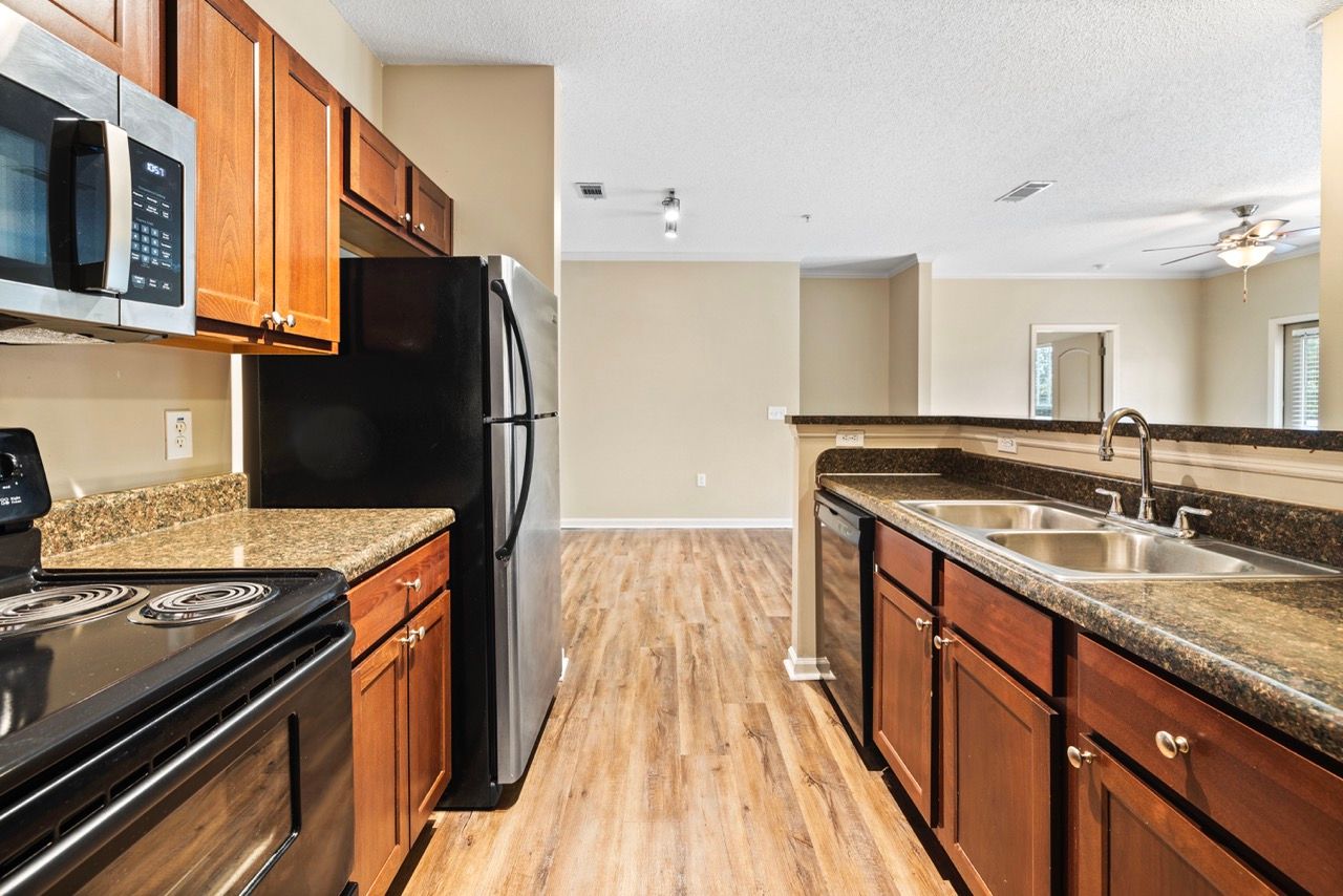 Open-concept kitchen with granite counters, wood cabinets, and stainless steel appliances.