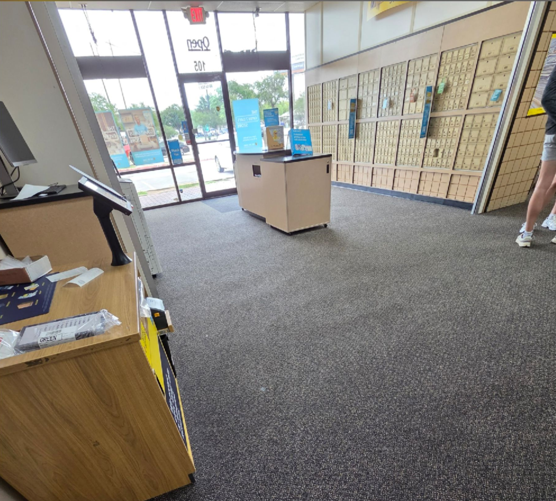 Interior of a lobby with a front desk, glass entrance, and wall of mailboxes in the background