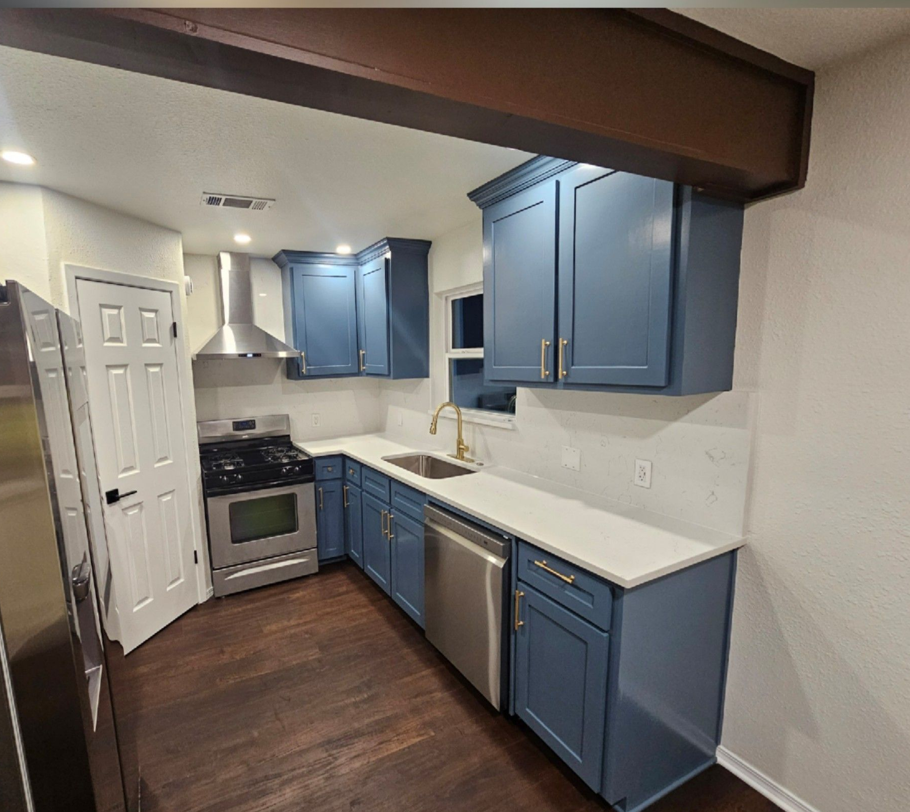 Laundry room with white cabinets above a washer and dryer, and a black cat resting on the dryer lid