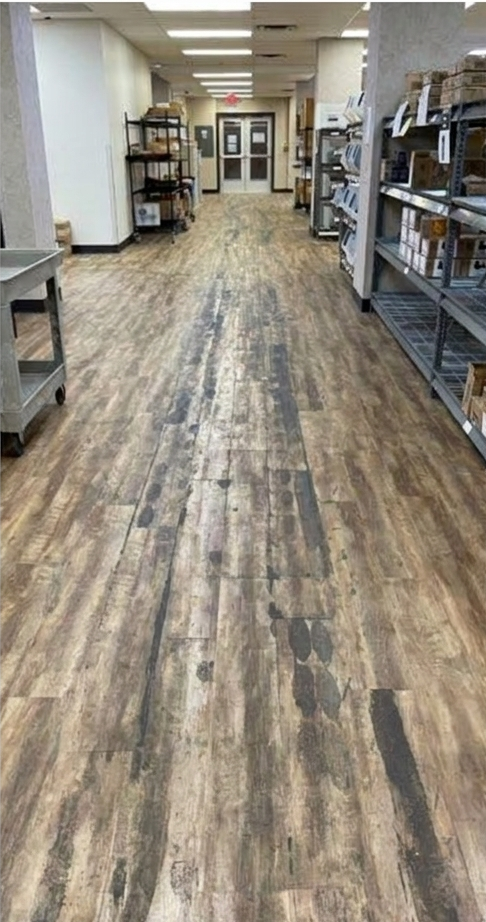 A long wood-floored aisle in a storage or retail space with shelves on both sides.