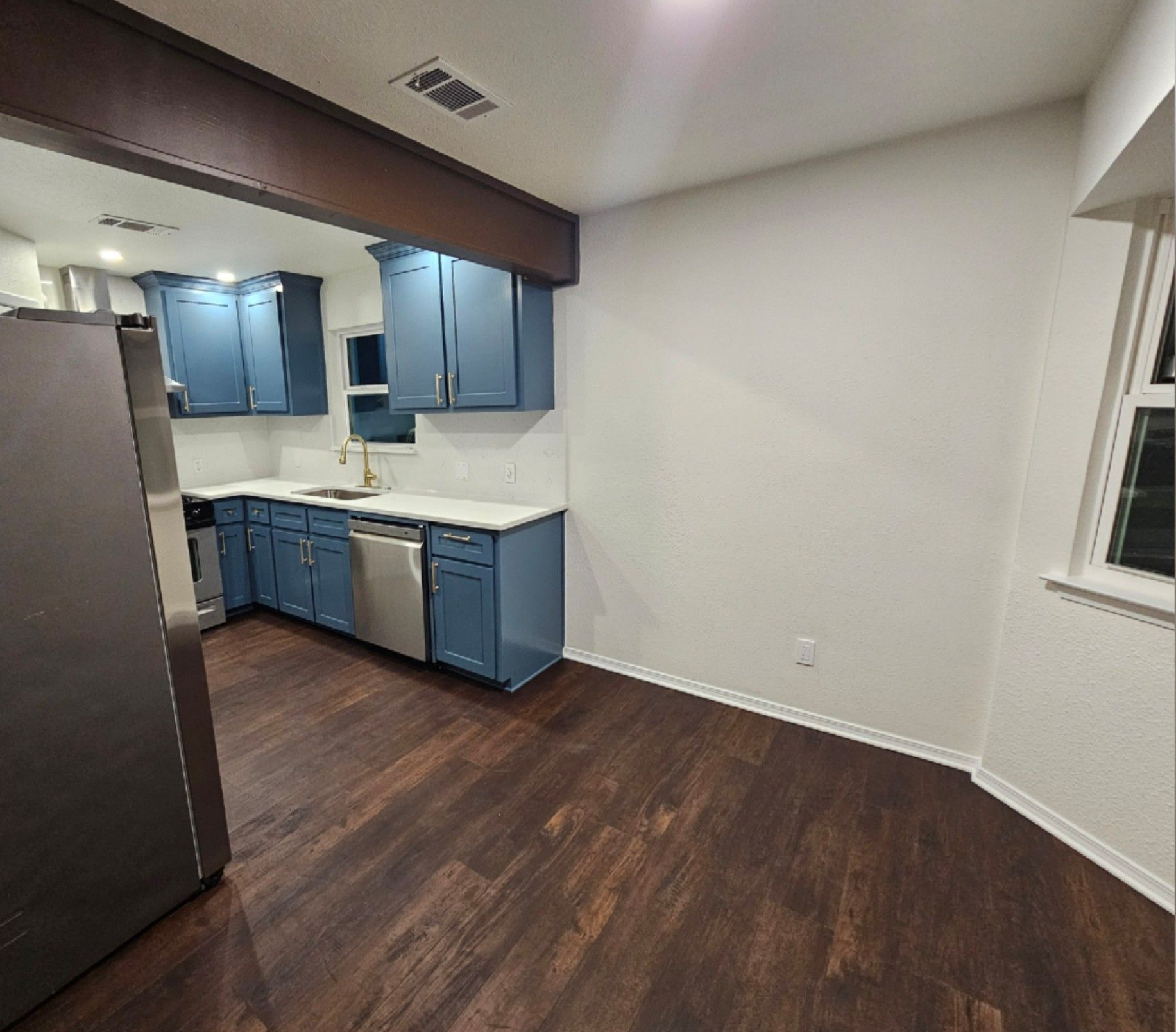 Laundry room with white cabinets above a washer and dryer, and a black cat resting on the dryer lid