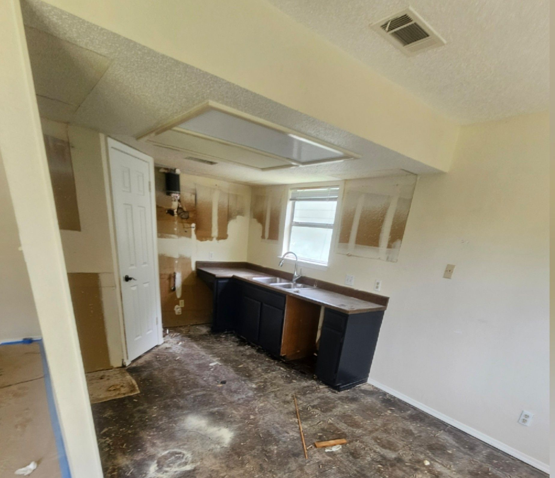 Empty wall with a small white shelf, electrical outlet, and patterned tile on the right; slight wall staining.