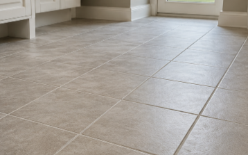 Empty beige tiled floor in a bright room with white furniture along the wall