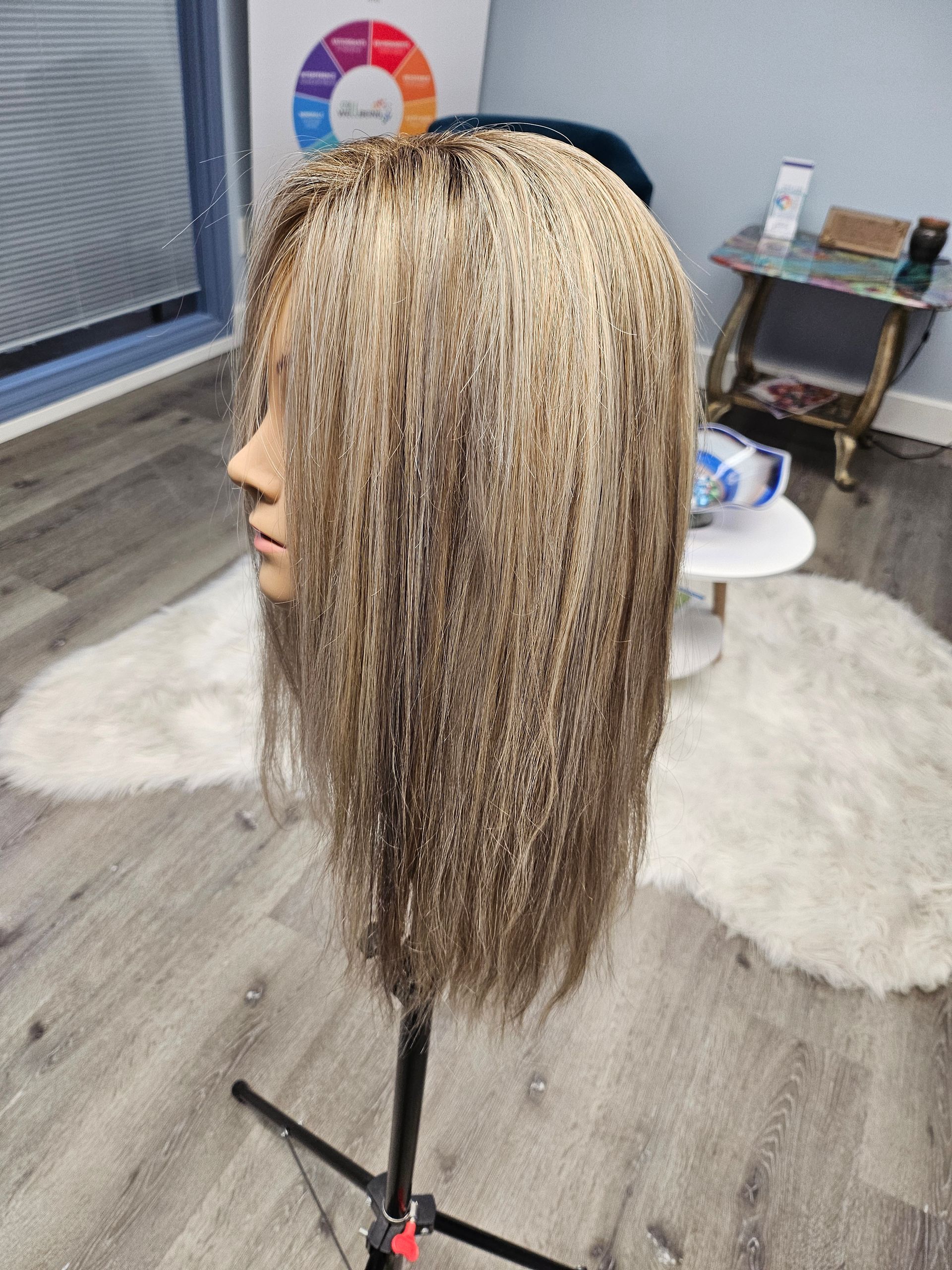 Mannequin head with long blonde braids on a stand in a salon setting.