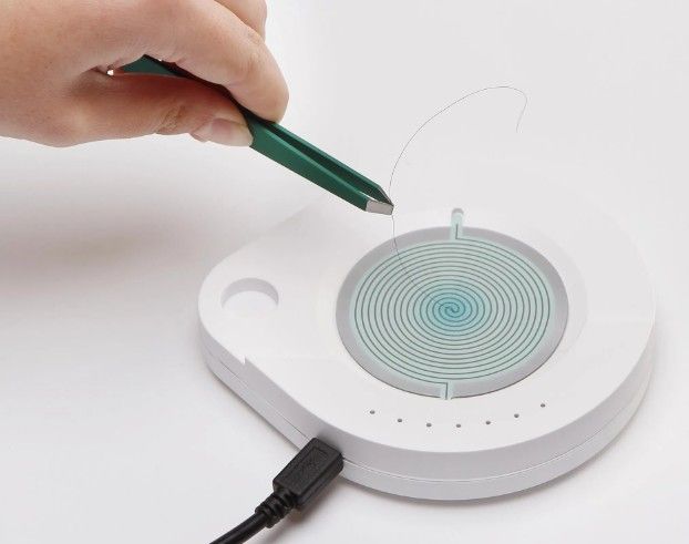 Hand drawing on a white wireless charging pad with a circular target and USB cable attached