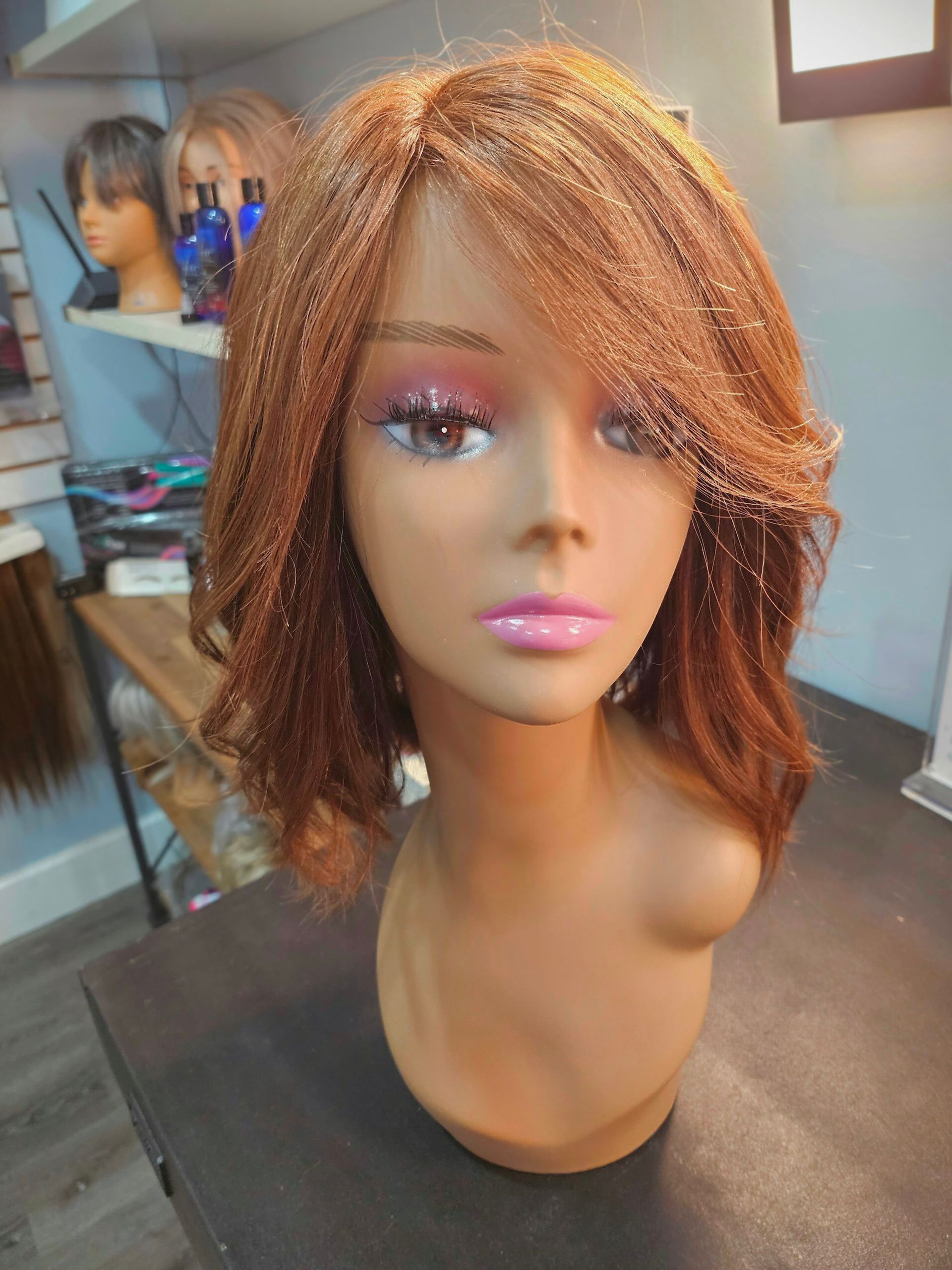 Mannequin head with short copper curls and pink makeup in a salon display