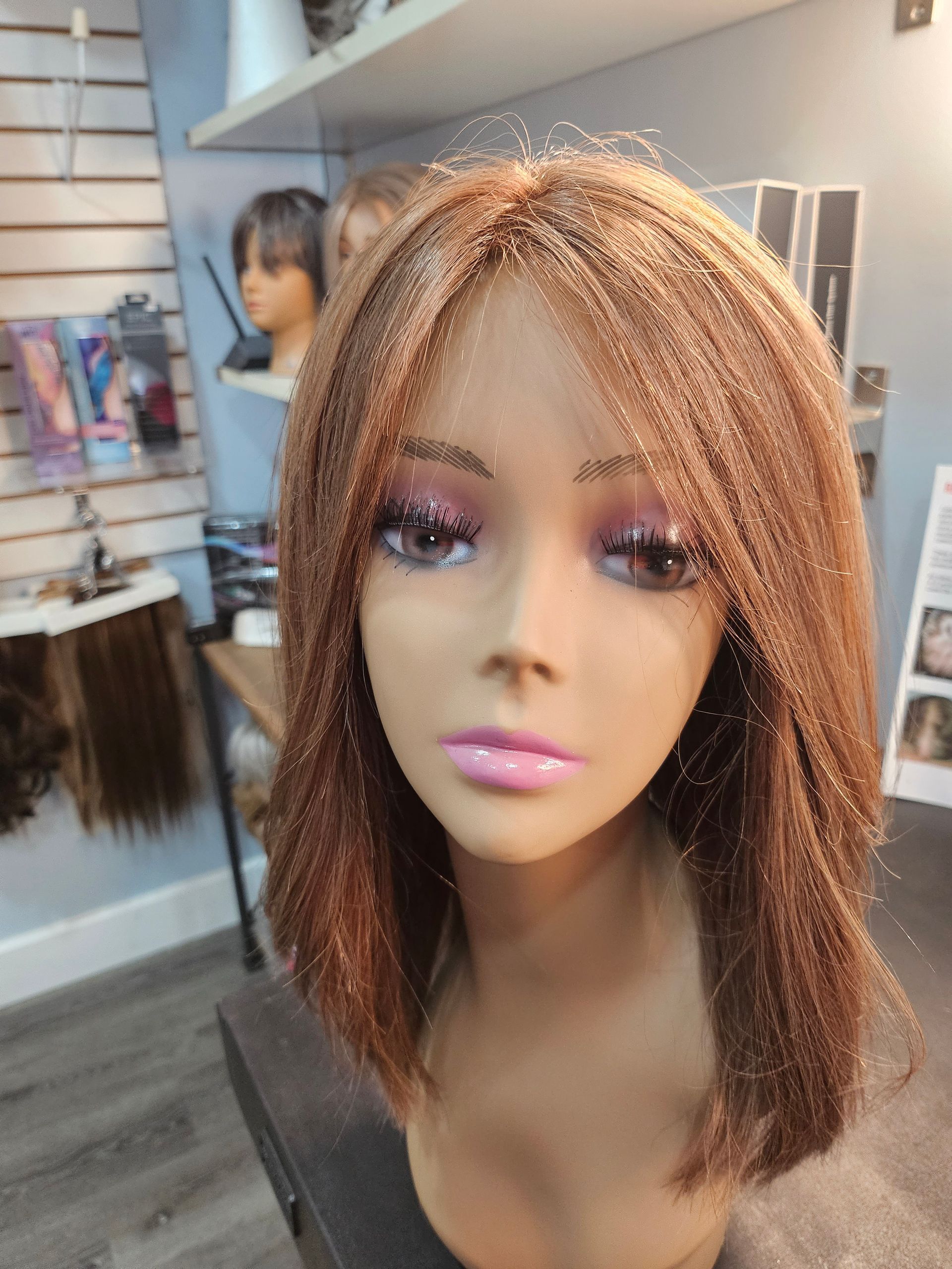 Mannequin head with layered auburn hair and makeup in a wig shop display