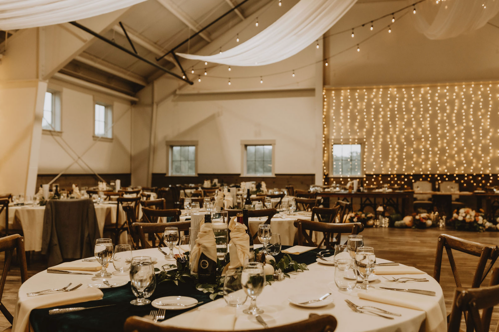 A large room with tables and chairs set up for a wedding reception.
