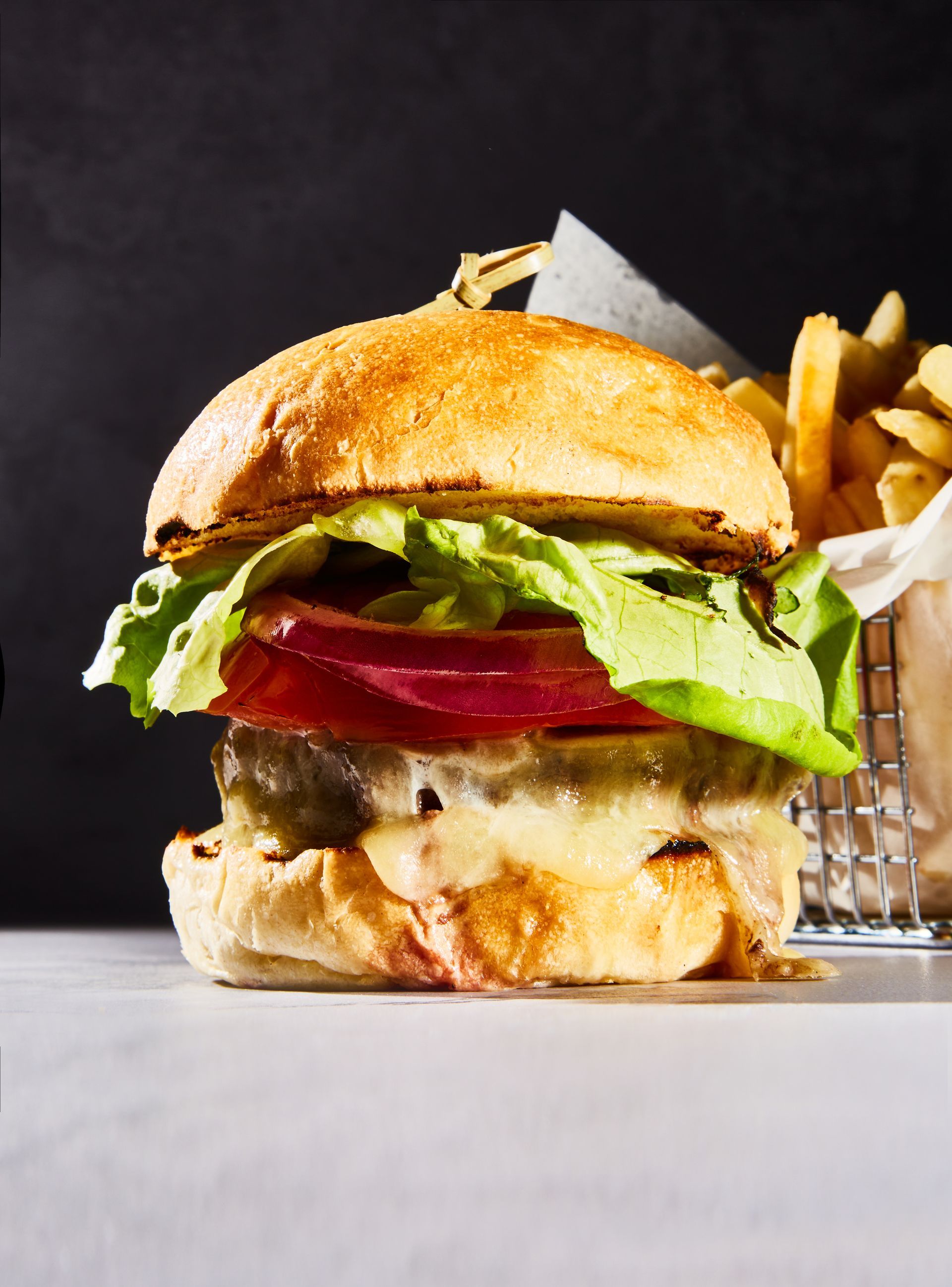 A close up of a hamburger and french fries on a table.