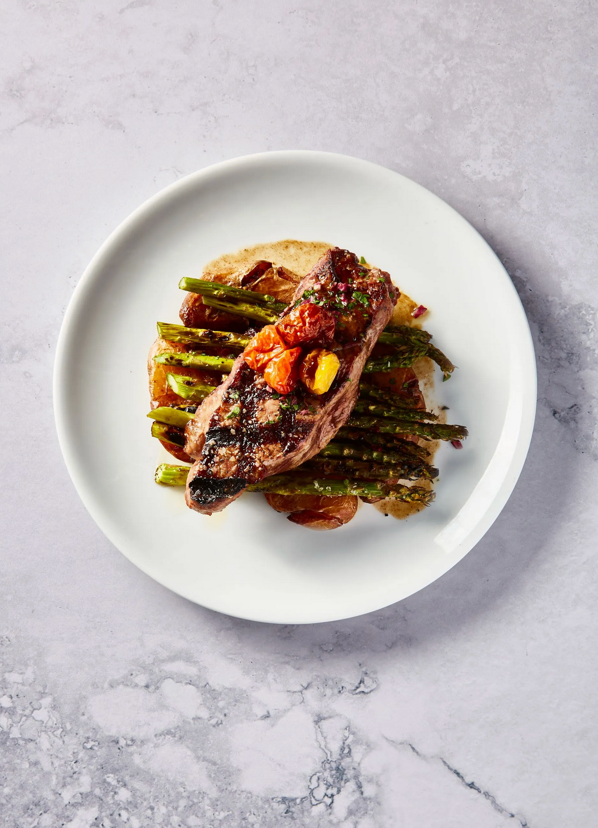 A white plate topped with a steak and asparagus on a table.
