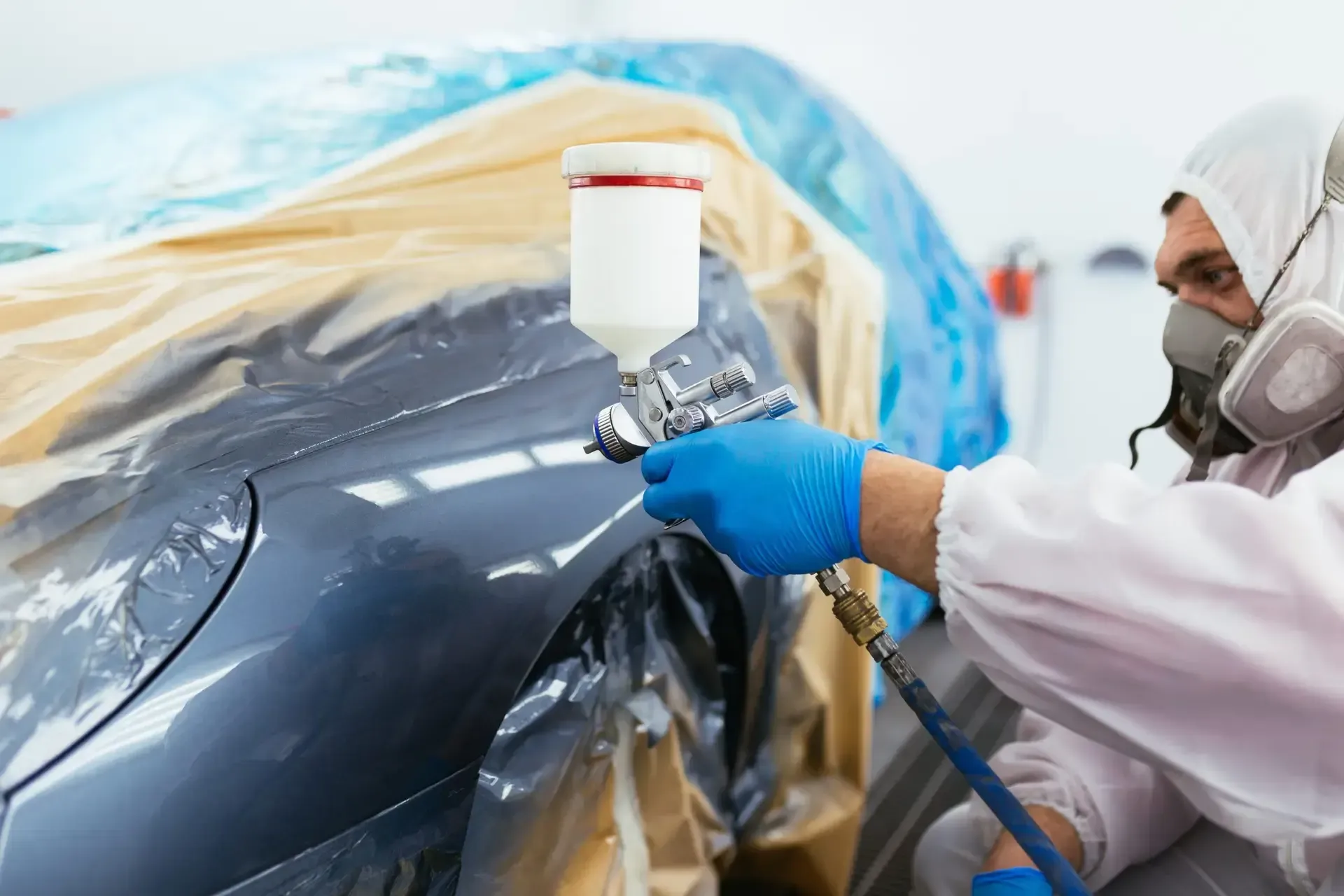 A man is spray painting a car in a garage.