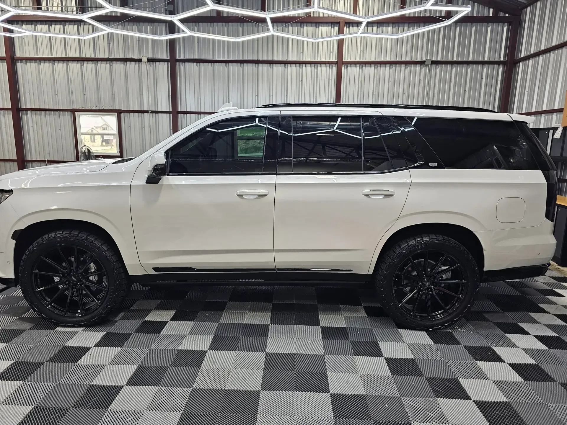 A white suv is parked in a garage on a checkered floor.