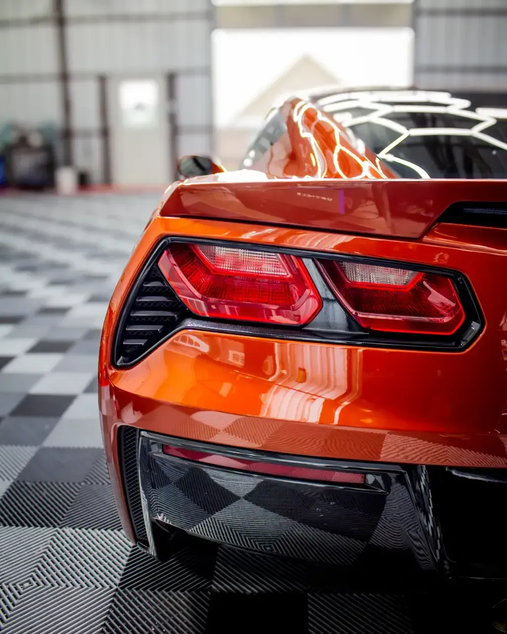 A close up of the back of an orange sports car in a garage.