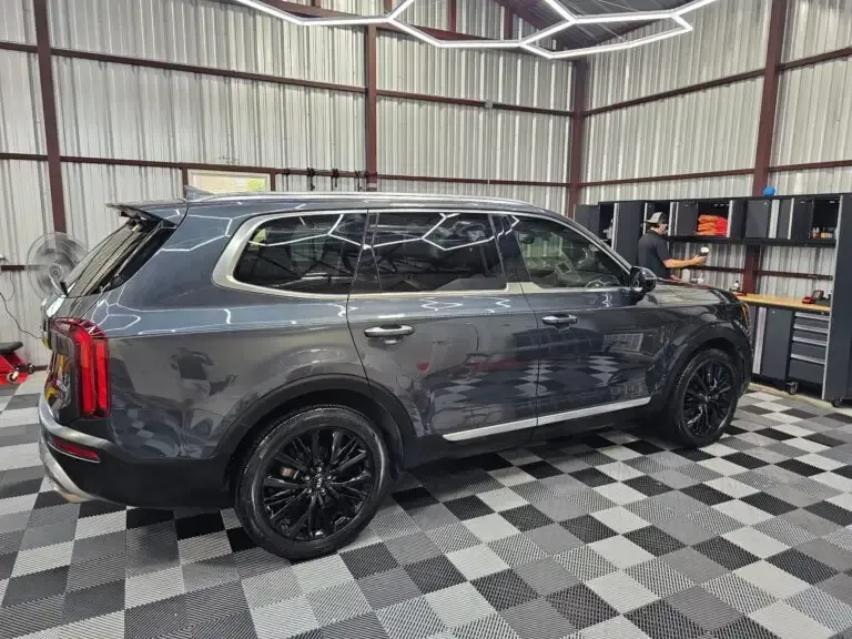 A gray suv is parked in a garage with a checkered floor.