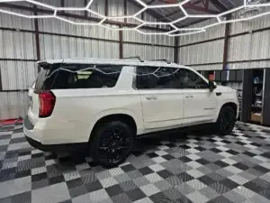 A white suv is parked in a garage with a checkered floor.