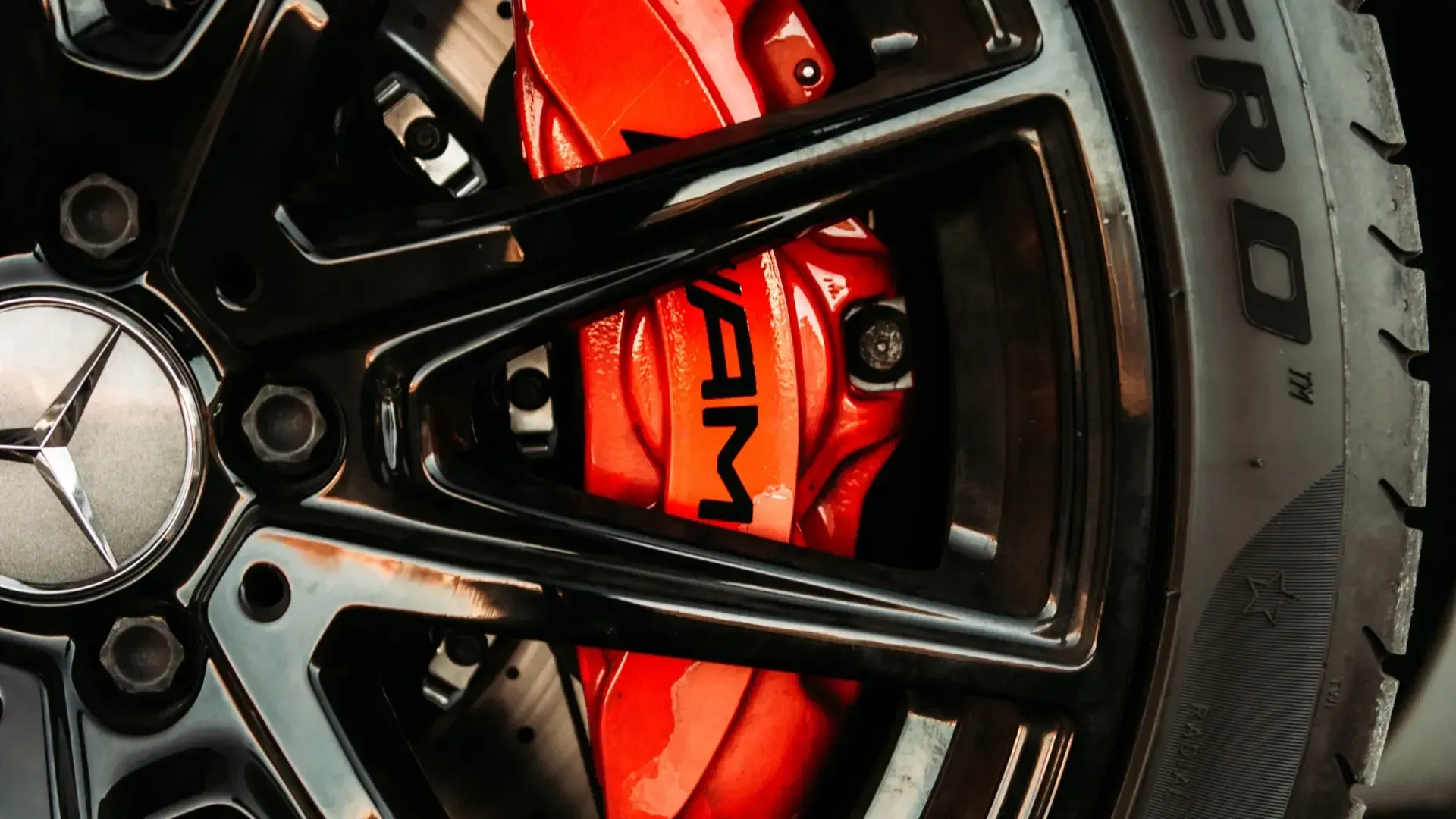 A close up of a mercedes wheel with a red brake caliper