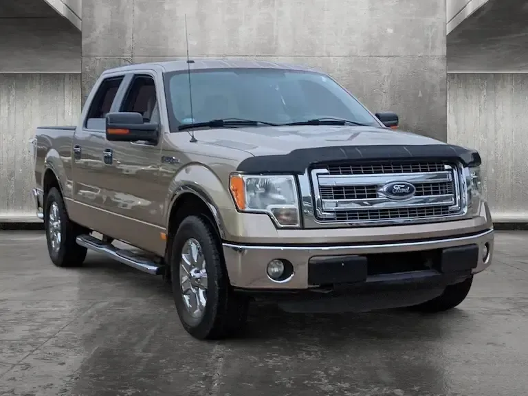 A ford f150 pickup truck is parked in front of a concrete wall.