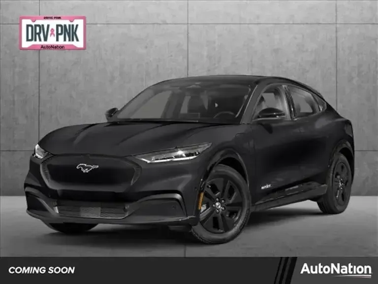 A black ford mustang mach e is sitting in front of a concrete wall.