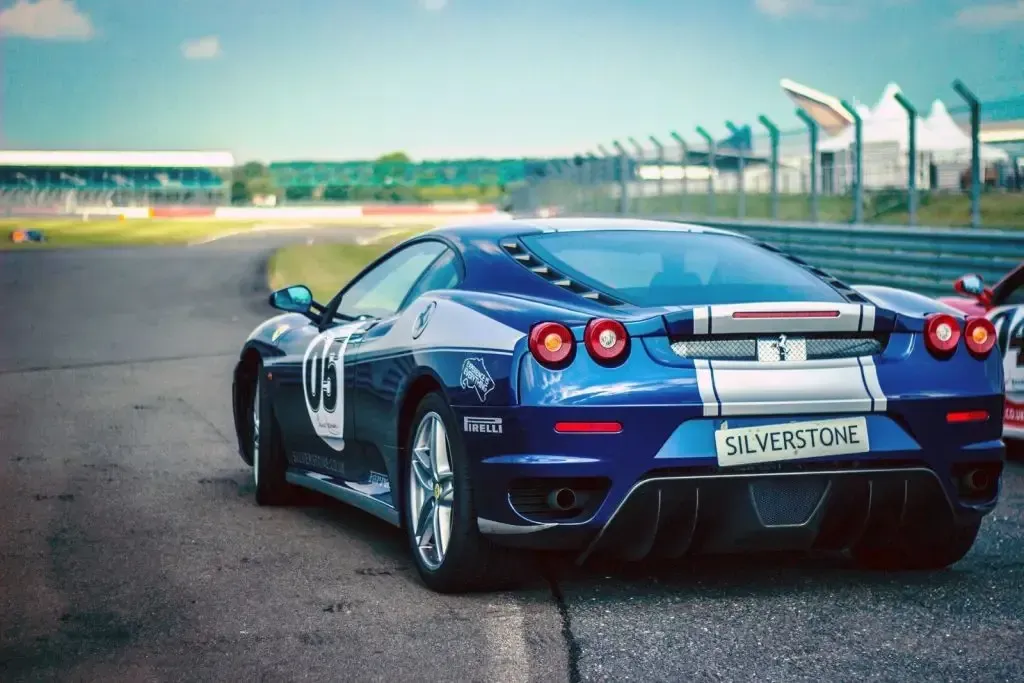 A blue sports car is parked on the side of a race track.