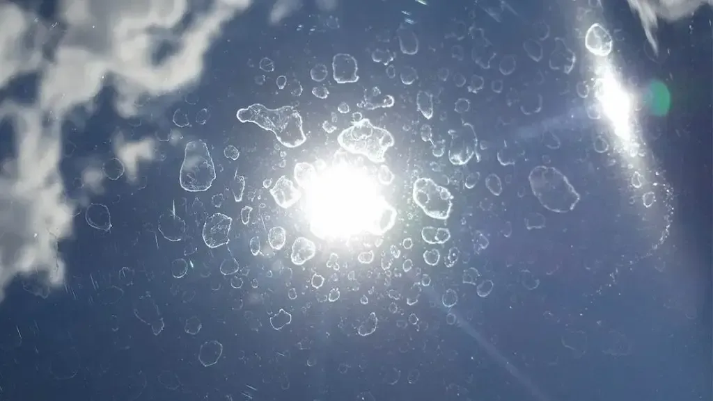 The sun is shining through the clouds and bubbles are floating in the air.