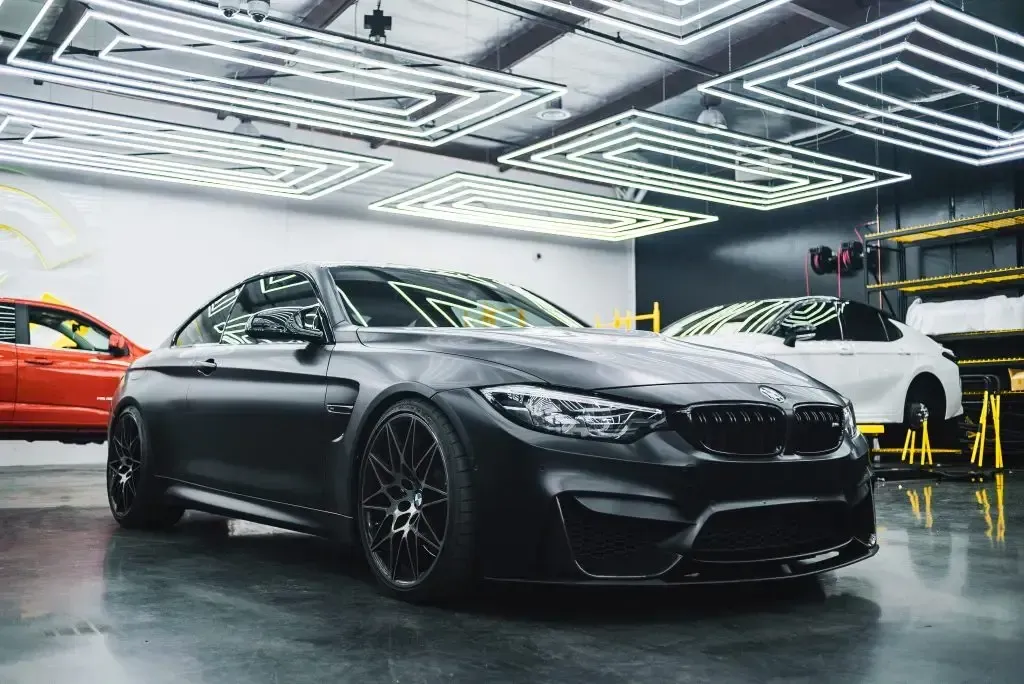 A black bmw m4 is parked in a garage.