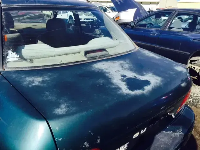 A green car with the letters b on the trunk