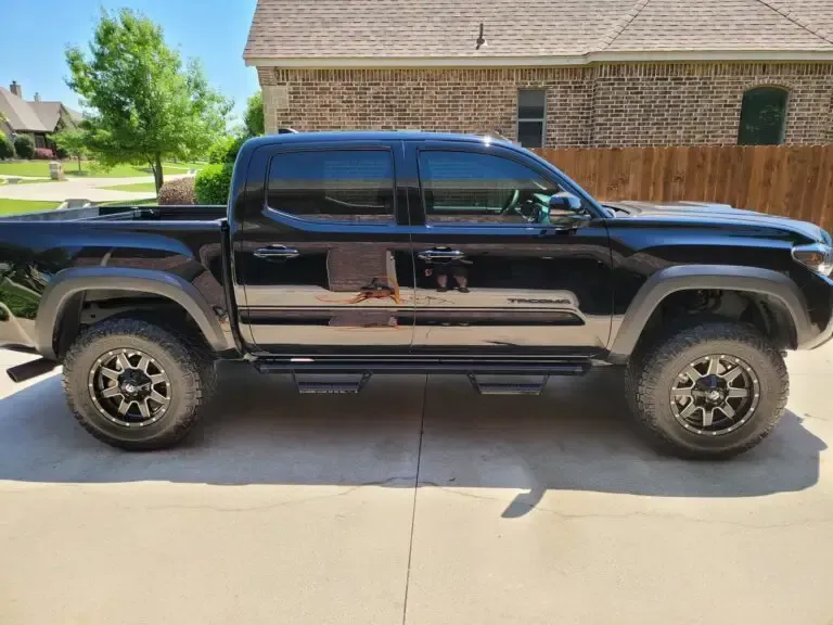 A black truck is parked in a driveway in front of a house.