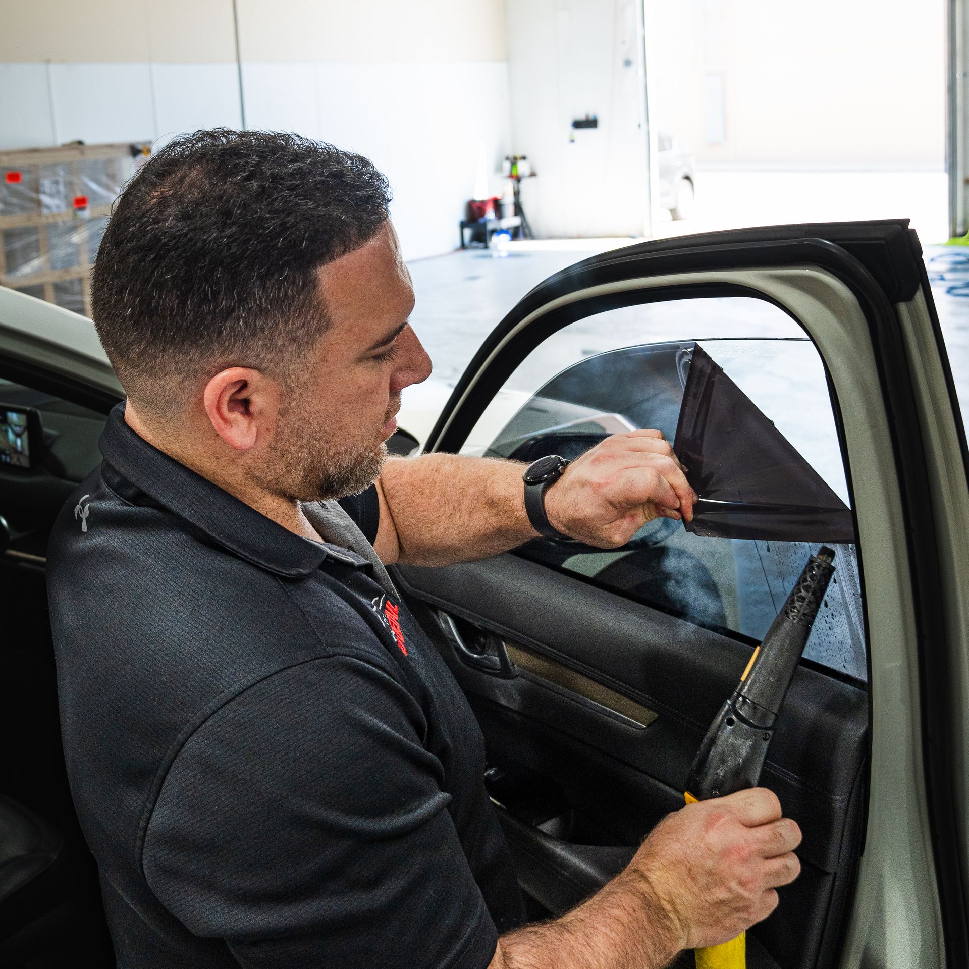 A man is sitting in a car holding a pair of scissors.