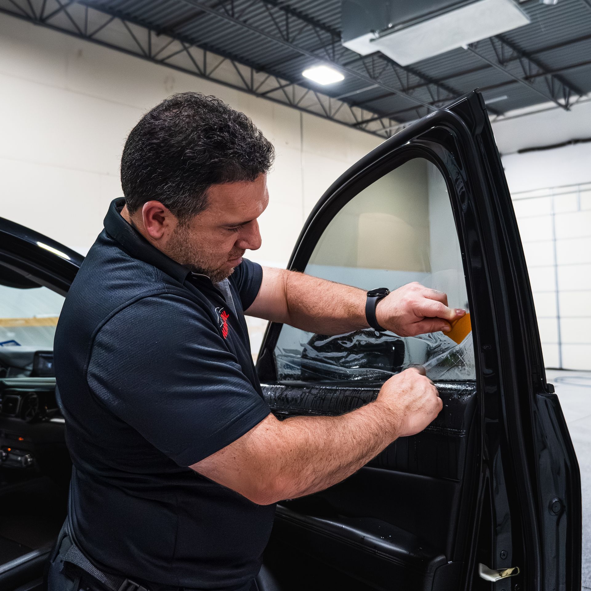 A man in a black shirt is working on a car door