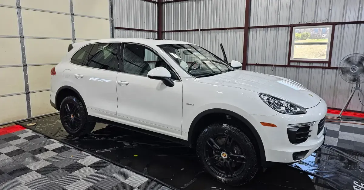 A white porsche cayenne is parked in a garage.