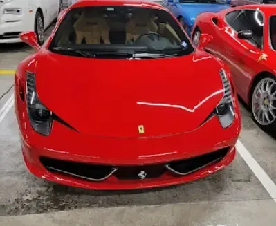 A red ferrari is parked in a parking lot