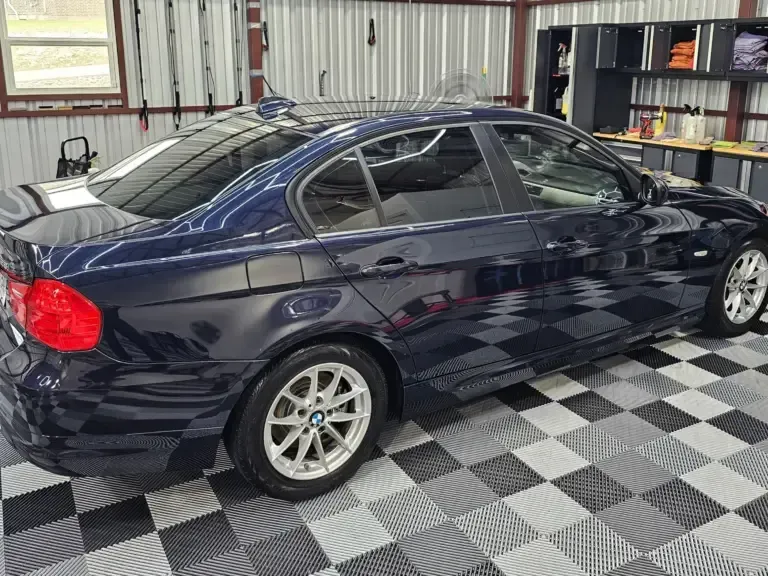 A blue car is parked in a garage on a checkered floor.