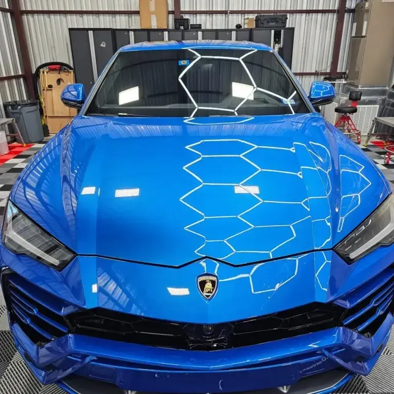 A blue lamborghini urus is parked in a garage