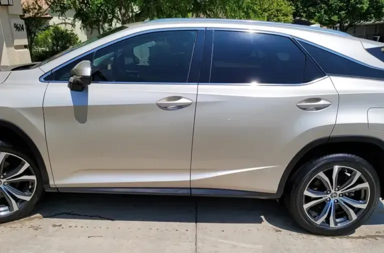 A silver lexus rx is parked on the side of the road.