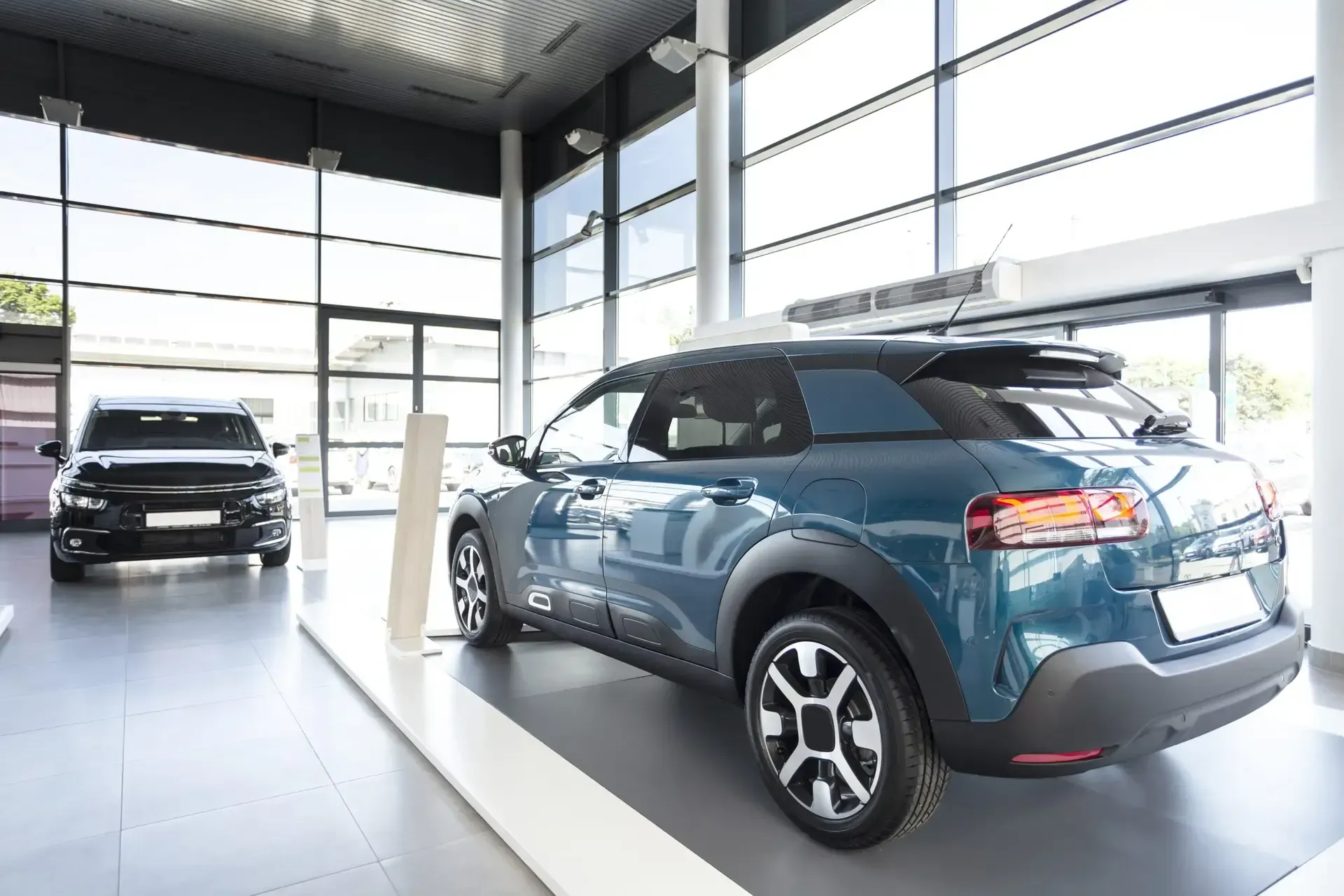 Two cars are displayed in a car showroom.