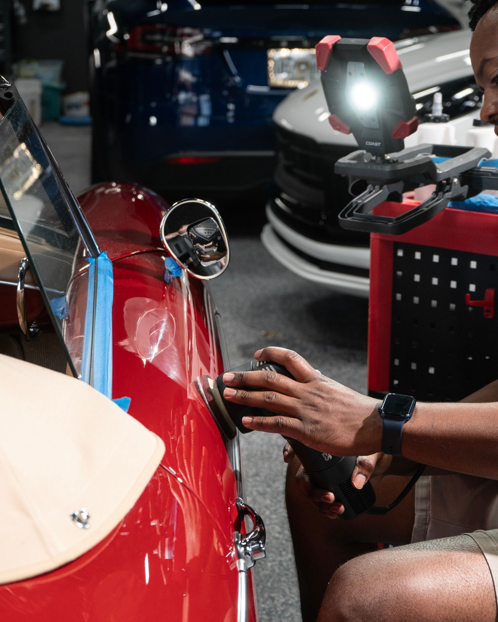 A man is working on a red car in a garage