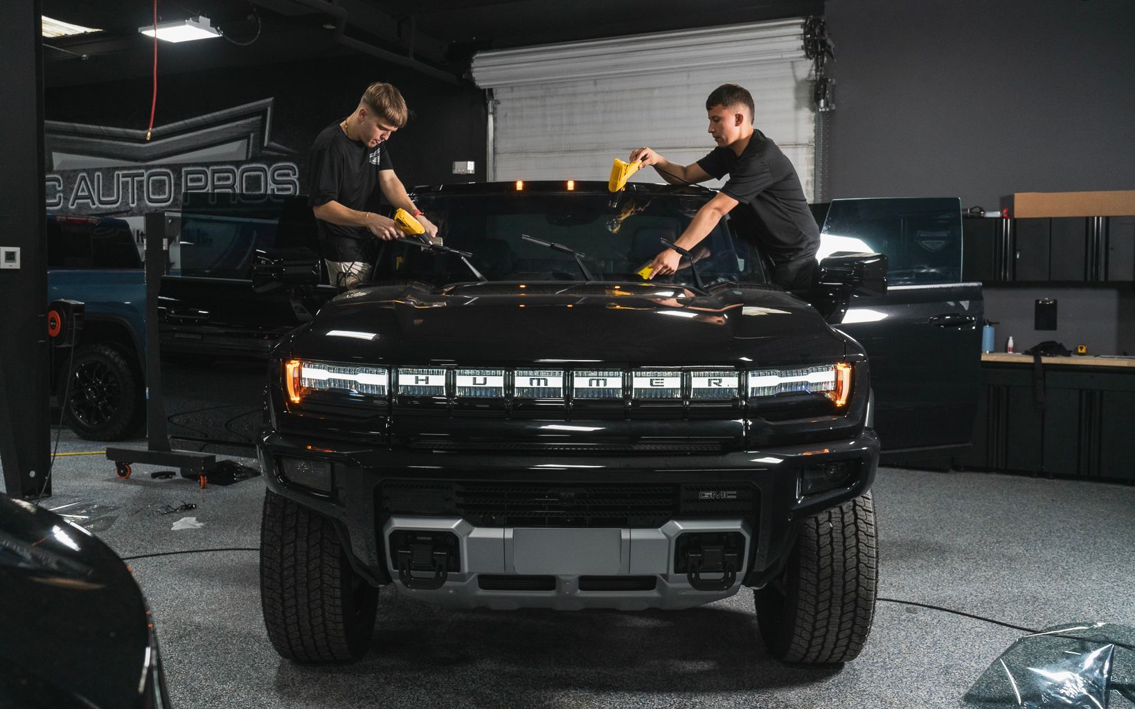 Two men are working on a black suv in a garage.