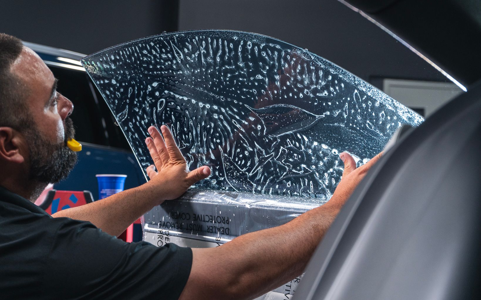 A man is applying window tinting to a car window.